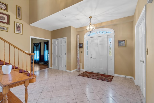 foyer featuring baseboards, stairway, and light tile patterned floors