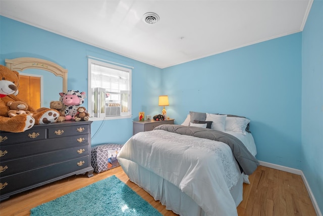 bedroom featuring baseboards, visible vents, crown molding, and light wood-style floors