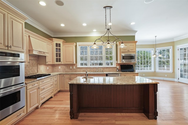 kitchen with crown molding, cream cabinets, a sink, glass insert cabinets, and stainless steel appliances