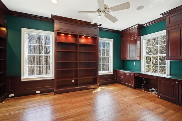 unfurnished office with ceiling fan, visible vents, built in study area, ornamental molding, and light wood-style flooring