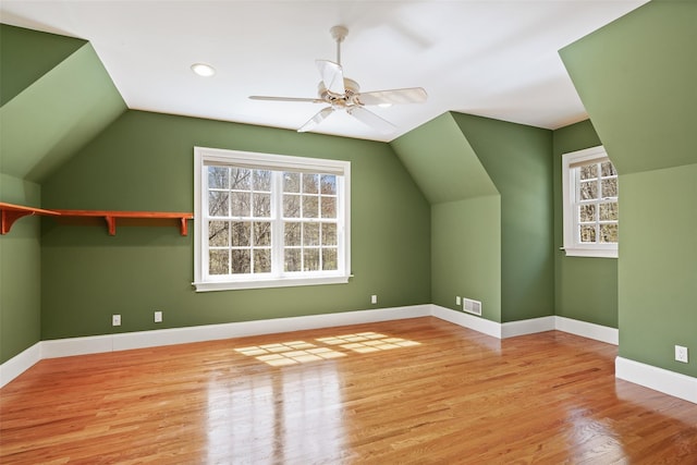 additional living space featuring a ceiling fan, visible vents, wood finished floors, baseboards, and lofted ceiling