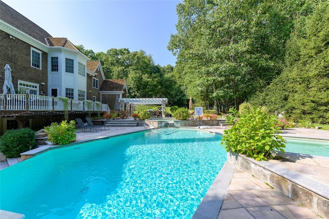 outdoor pool with a pergola, a patio, and a deck