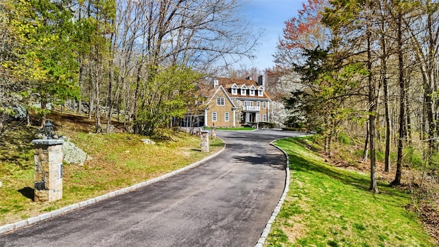 view of front facade with a chimney, a front yard, and aphalt driveway