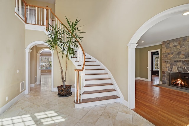 stairway with arched walkways, ornamental molding, ornate columns, and visible vents