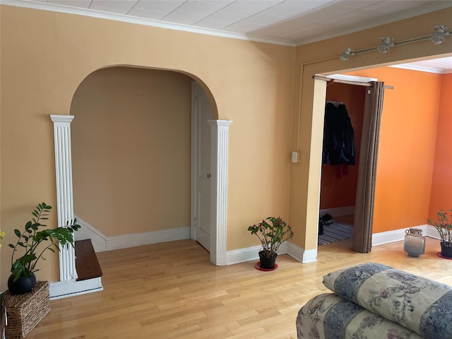 248-29 88th Rd, Bellerose, NY 11426 - unfurnished living room featuring arched walkways, light wood-style flooring, ornamental molding, decorative columns, and baseboards