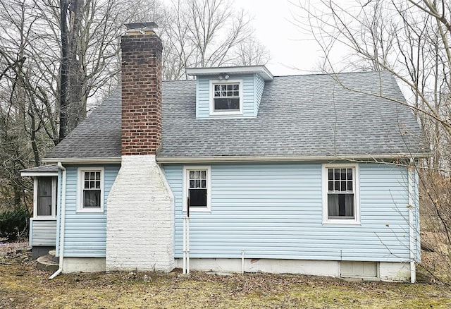 view of side of home with roof with shingles and a chimney