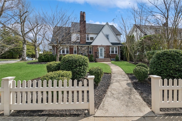 view of front of house featuring brick siding, a front yard, a fenced front yard, and a chimney