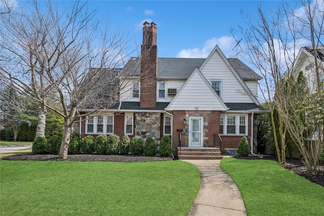 view of front of home with a front lawn, a chimney, a shingled roof, and brick siding
