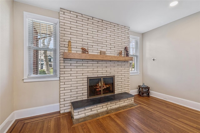 unfurnished living room with baseboards, wood finished floors, and a wealth of natural light