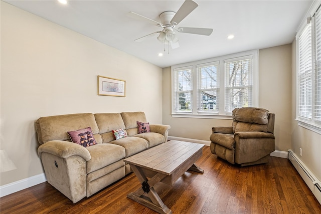 living area featuring a ceiling fan, dark wood-style flooring, plenty of natural light, and a baseboard heating unit