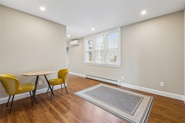 sitting room with baseboards, wood finished floors, a baseboard heating unit, and a wall unit AC