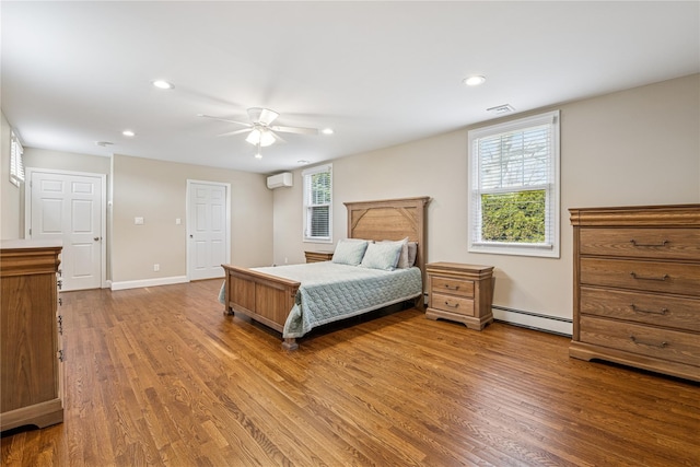 bedroom with a wall unit AC, a baseboard heating unit, recessed lighting, baseboards, and wood finished floors