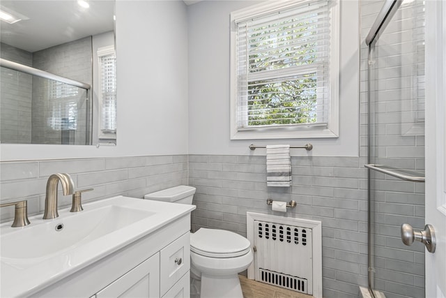full bathroom with tile walls, toilet, radiator heating unit, vanity, and a stall shower