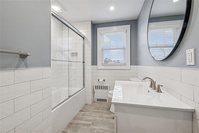 bathroom with radiator heating unit, toilet, vanity, and tile walls