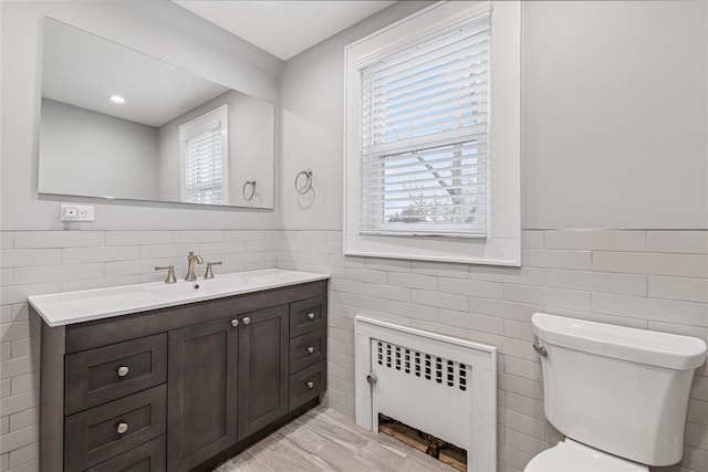 bathroom featuring wainscoting, radiator heating unit, and tile walls