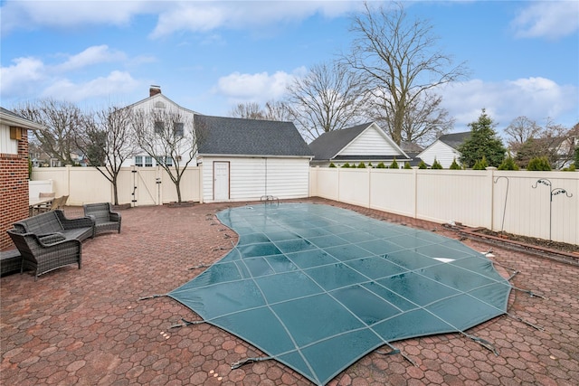 view of swimming pool with an outbuilding, a patio, a fenced backyard, a fenced in pool, and a gate