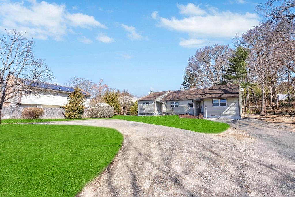 view of front of home featuring curved driveway, a front lawn, and fence