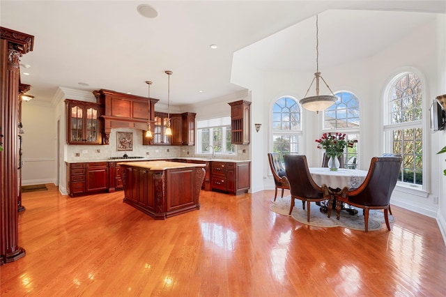 8 Tatem Way, Old Westbury, NY 11568 - kitchen with light countertops, a center island, a sink, light wood-style flooring, and decorative backsplash
