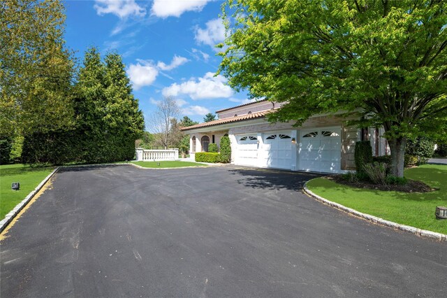 8 Tatem Way, Old Westbury, NY 11568 - view of front of home with asphalt driveway, an attached garage, and a front lawn