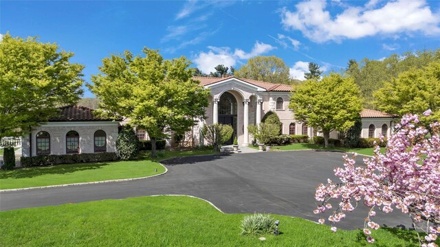 8 Tatem Way, Old Westbury, NY 11568 - mediterranean / spanish-style home with a tiled roof, a front yard, and curved driveway