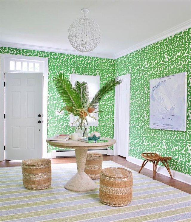 interior space with crown molding, wood finished floors, baseboards, baseboard heating, and wallpapered walls