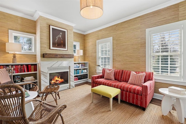 living area with crown molding, a premium fireplace, and wood finished floors