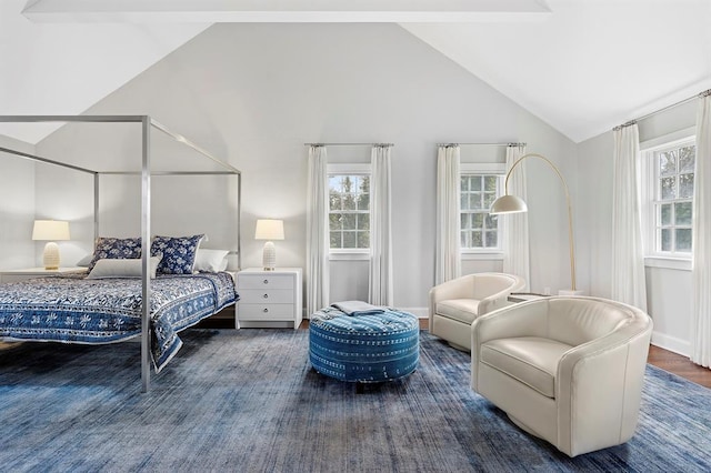bedroom with high vaulted ceiling and wood finished floors