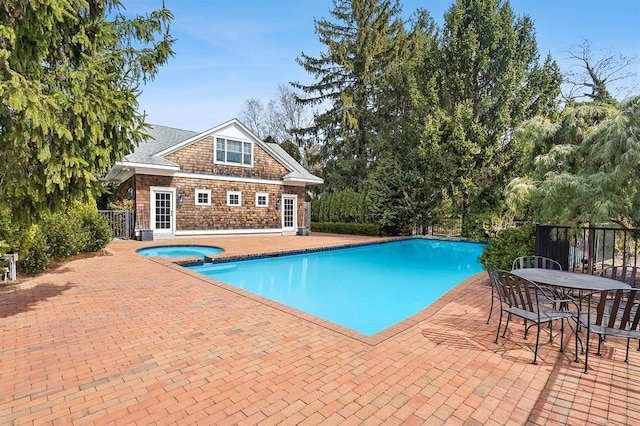 pool with an in ground hot tub, a patio area, an exterior structure, fence, and an outdoor structure