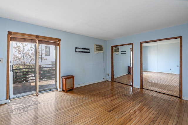 83-18 Parsons Blvd, Jamaica, NY 11431 - unfurnished bedroom featuring baseboards, access to exterior, an AC wall unit, light wood-style floors, and two closets