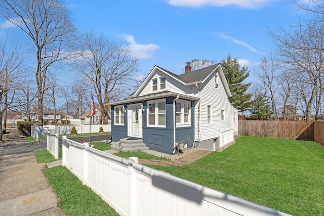 view of home's exterior featuring brick siding, a lawn, fence private yard, and a chimney