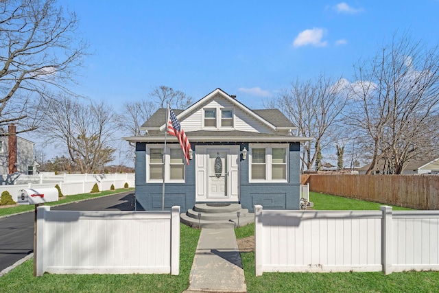 bungalow-style home with a fenced front yard and brick siding