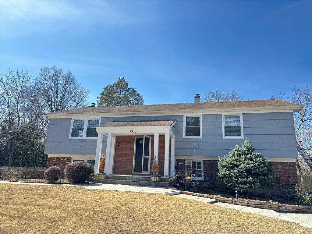split foyer home with brick siding and a front lawn
