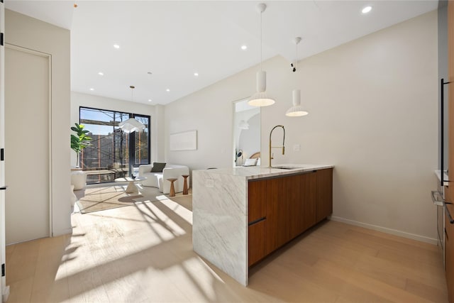 interior space with baseboards, recessed lighting, a sink, hanging light fixtures, and light wood-type flooring