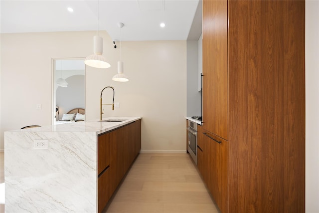 kitchen featuring brown cabinetry, light stone countertops, a peninsula, a sink, and modern cabinets