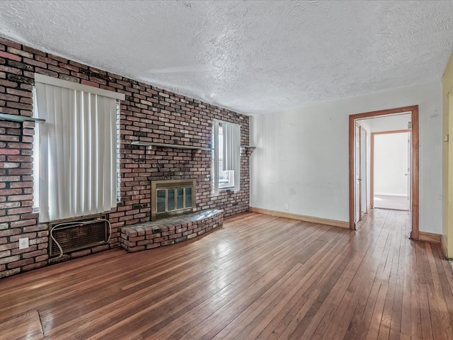 unfurnished living room featuring a brick fireplace, baseboards, and hardwood / wood-style flooring