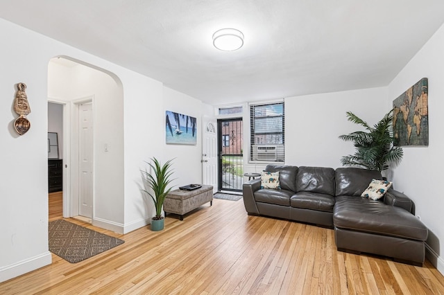 living room featuring arched walkways, hardwood / wood-style floors, and baseboards