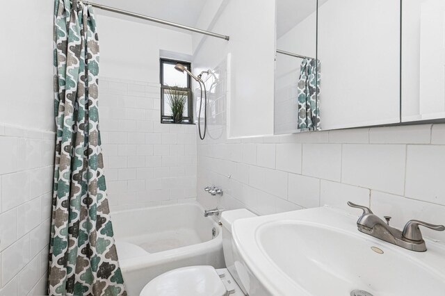 full bath featuring toilet, a sink, shower / bathtub combination with curtain, and tile walls
