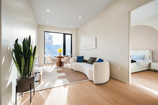 living area with radiator, baseboards, recessed lighting, wood finished floors, and arched walkways