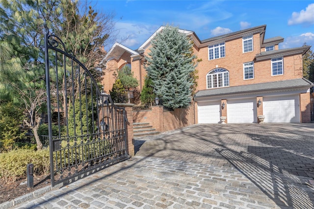 view of front facade with decorative driveway, an attached garage, brick siding, and stairway