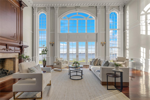 living area featuring a decorative wall, a high ceiling, plenty of natural light, a water view, and a fireplace