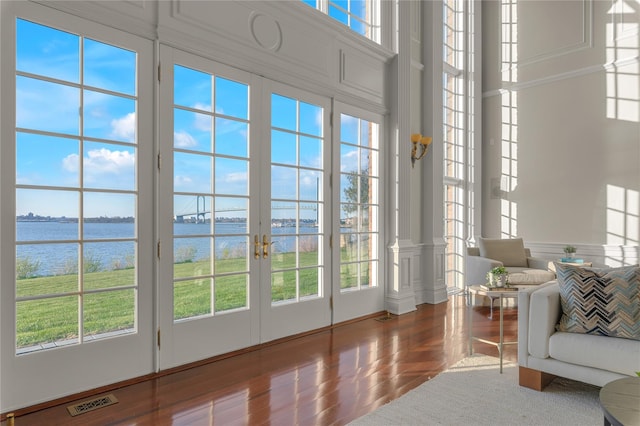 living room featuring a water view, wood finished floors, and french doors