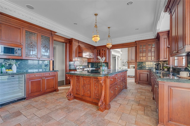 kitchen with stainless steel microwave, custom range hood, backsplash, stone tile flooring, and ornamental molding