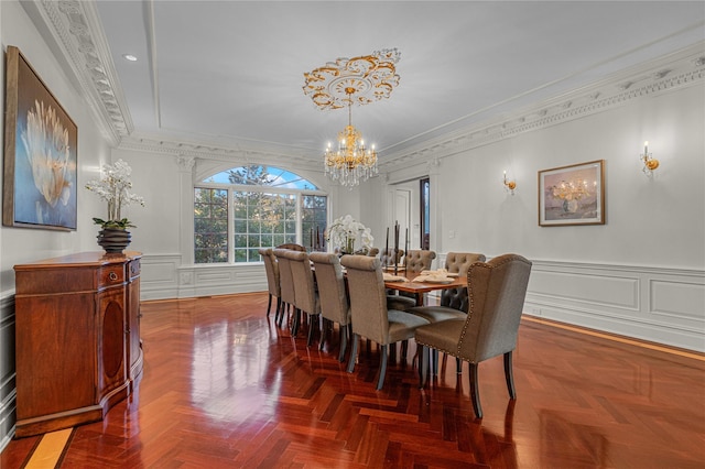 dining area with a chandelier, crown molding, a decorative wall, and a wainscoted wall