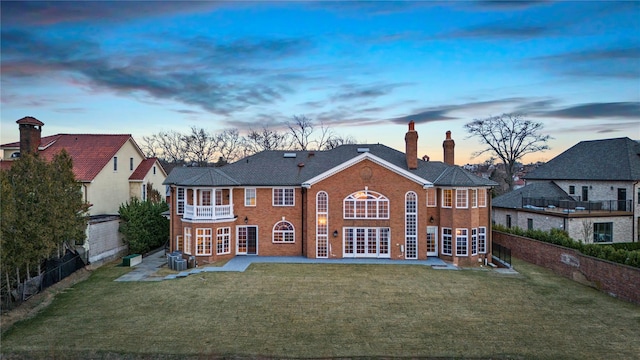 rear view of property with french doors, a patio, a balcony, and a lawn