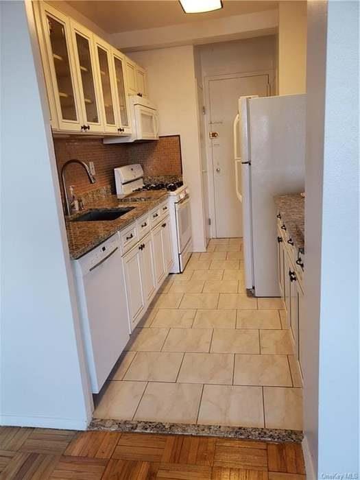 6 Fordham Hill Oval Unit 15F, Bronx, NY 10468 - kitchen featuring white appliances, tasteful backsplash, dark stone counters, glass insert cabinets, and white cabinets