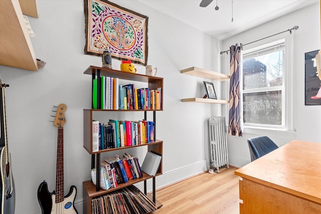 office space with baseboards, wood finished floors, radiator heating unit, and a ceiling fan