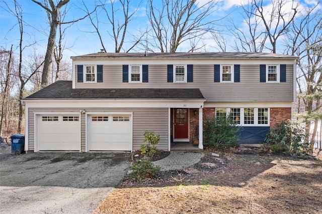 traditional home with brick siding, a garage, and aphalt driveway