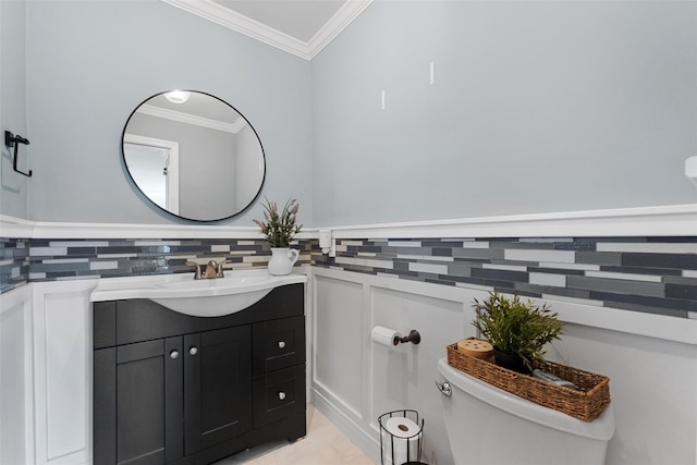bathroom with vanity, ornamental molding, a wainscoted wall, and toilet