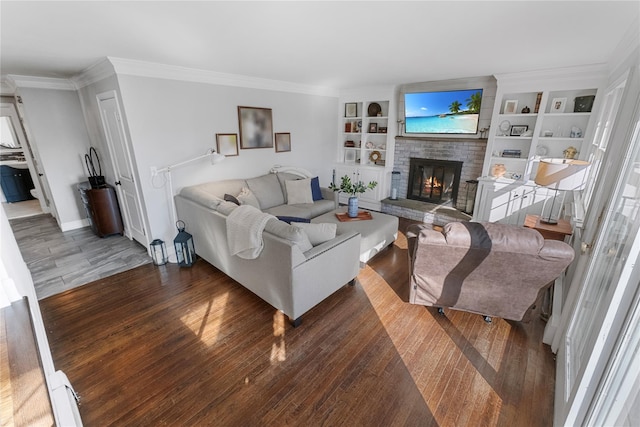 living room with a brick fireplace, baseboards, built in shelves, and wood finished floors