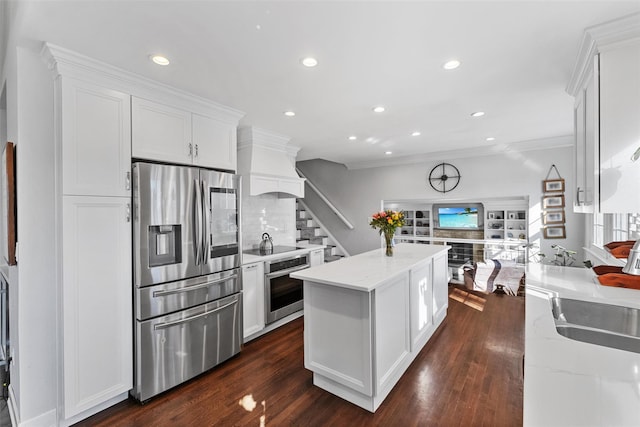 kitchen with a kitchen island, appliances with stainless steel finishes, a sink, custom exhaust hood, and white cabinetry
